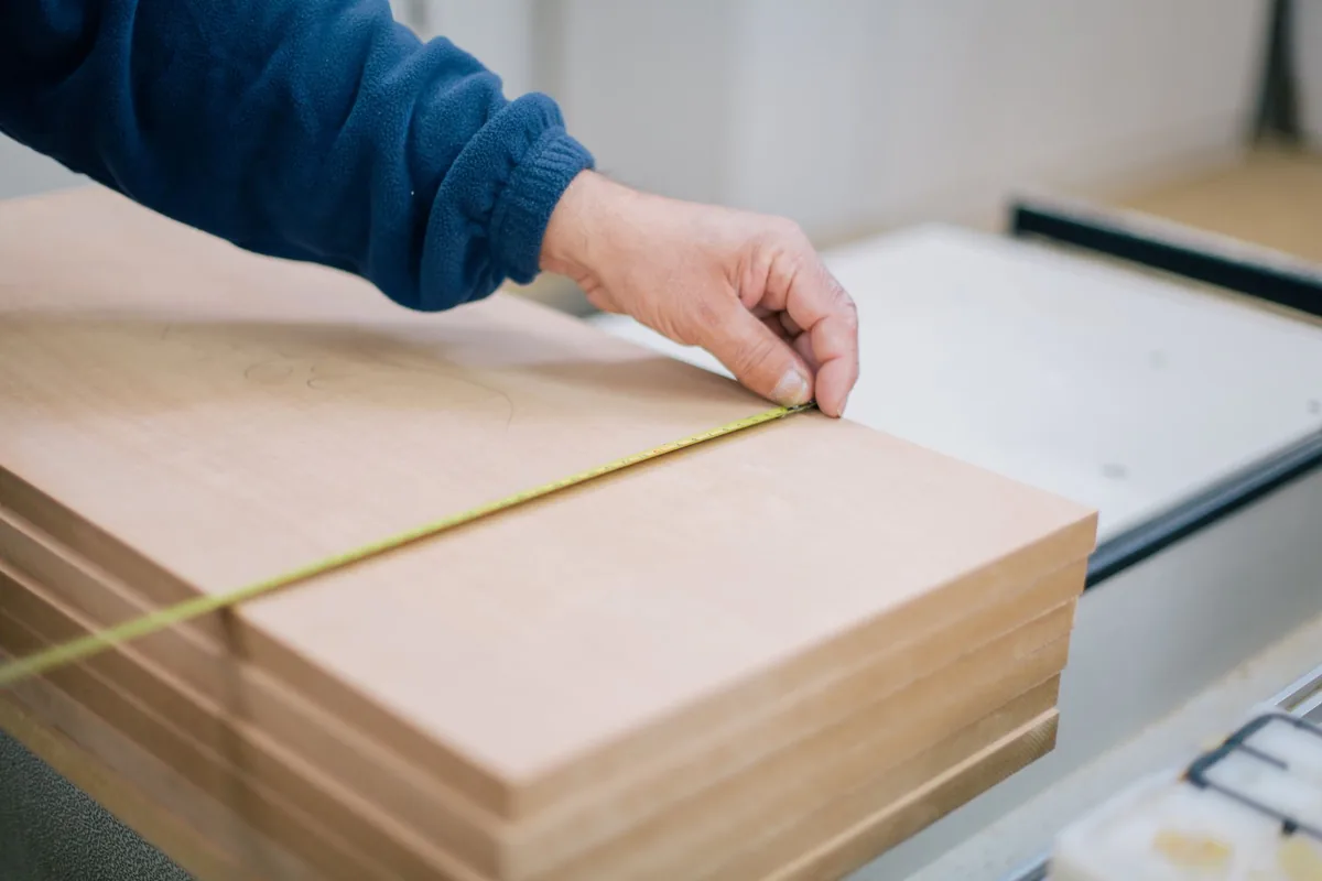 Measuring a sheet of timber on the bench before cutting