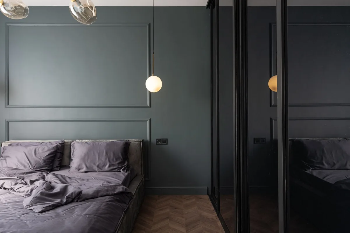 Fitted wardrobes with panelled doors in a dark green bedroom