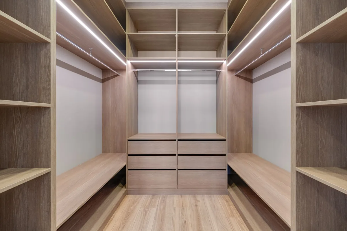 Walk-in wardrobe fitted out in oak with open shelving and hanging rails