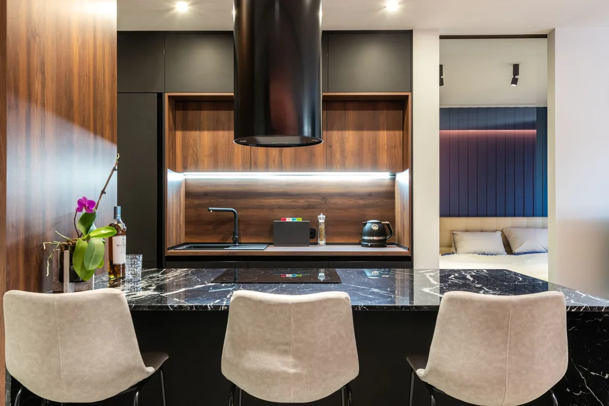 Dark kitchen with a stone island and warm under-cabinet lighting