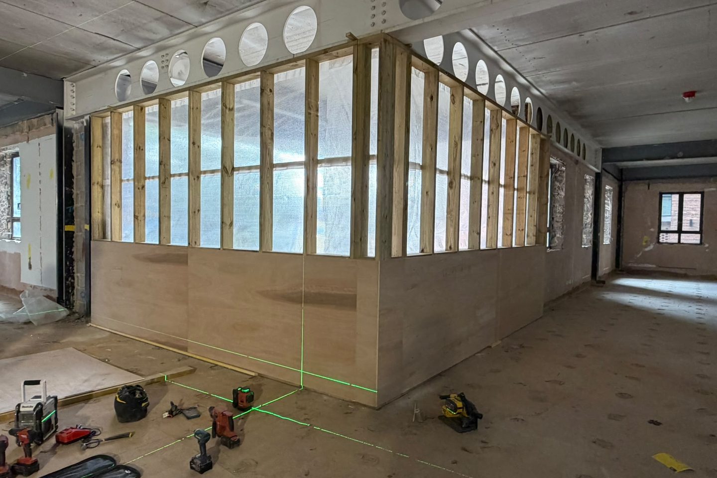 Timber stud partition framed and boarded in ply to dado height on an office strip-out